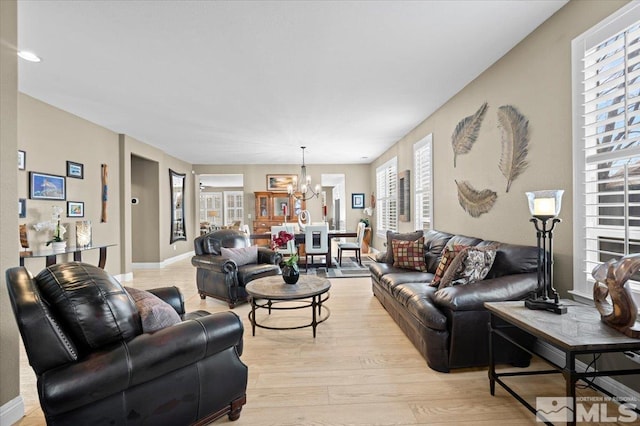 living area featuring a chandelier, baseboards, and light wood-style floors