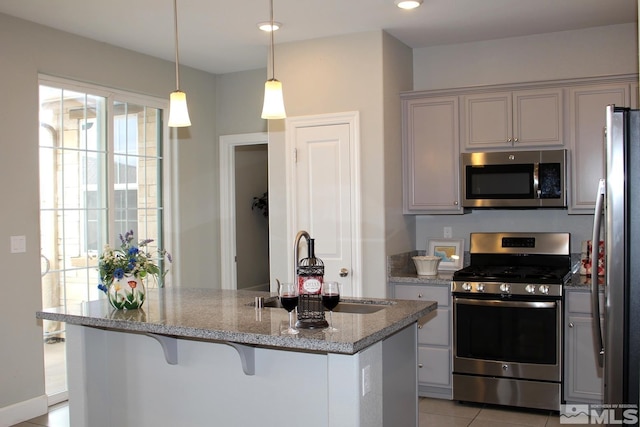 kitchen with light stone counters, light tile patterned flooring, a sink, hanging light fixtures, and appliances with stainless steel finishes