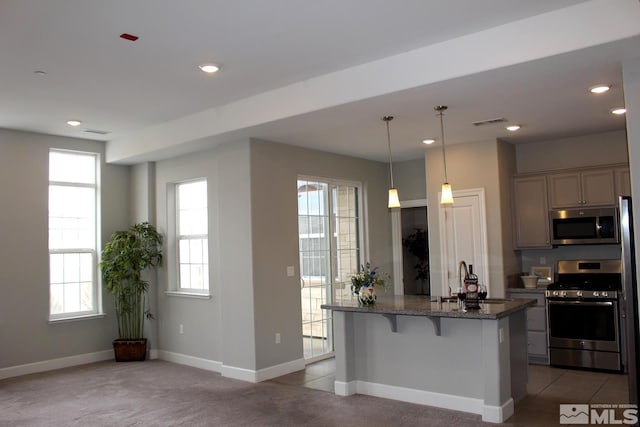 kitchen with dark stone counters, a breakfast bar area, stainless steel appliances, a sink, and recessed lighting