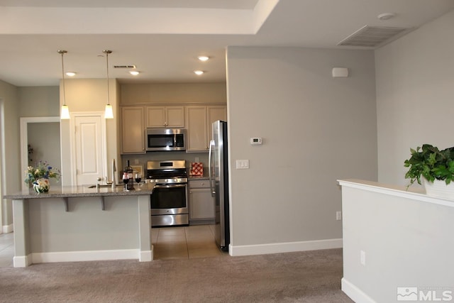 kitchen featuring light carpet, stainless steel appliances, visible vents, and a kitchen breakfast bar