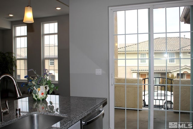 kitchen featuring stainless steel dishwasher, pendant lighting, and a sink