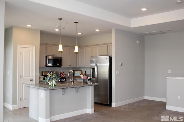 kitchen featuring an island with sink, baseboards, stainless steel appliances, and dark stone countertops