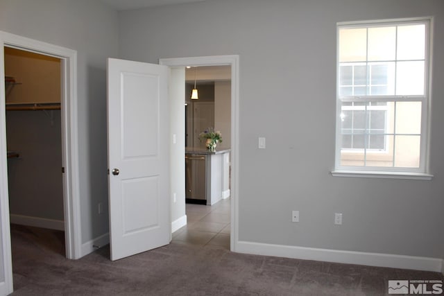 unfurnished bedroom featuring carpet, baseboards, a walk in closet, and a closet