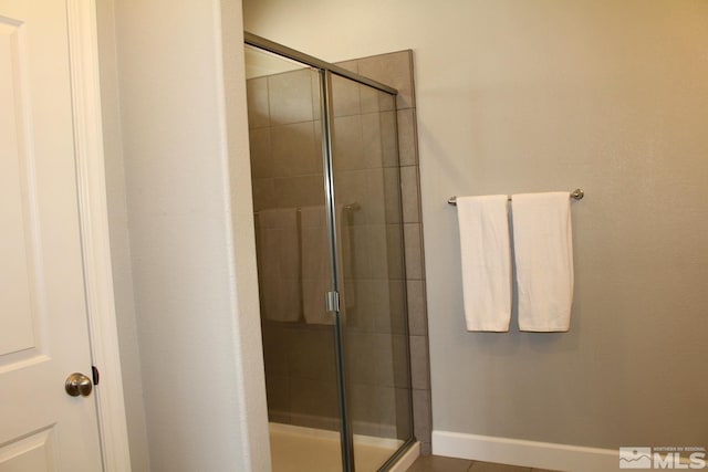 bathroom with a shower stall and baseboards