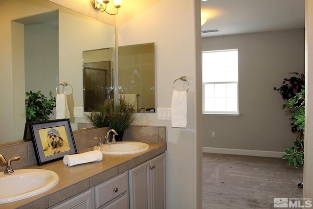 bathroom with double vanity, a sink, visible vents, and baseboards
