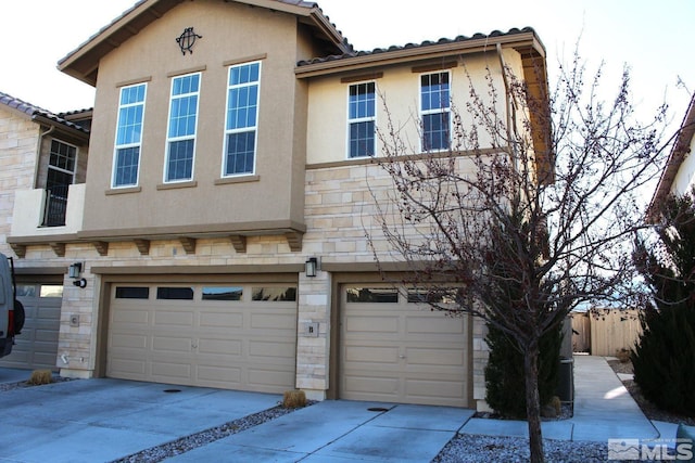 townhome / multi-family property with stone siding, concrete driveway, an attached garage, and stucco siding