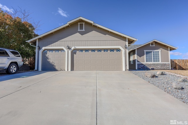 ranch-style home with driveway, stone siding, an attached garage, and fence