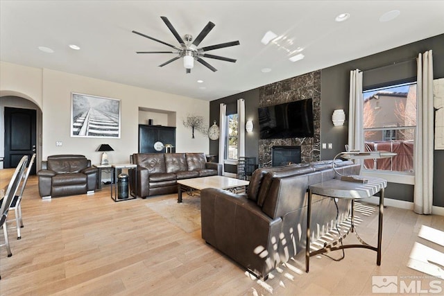 living room featuring light wood-type flooring, a tile fireplace, ceiling fan, and recessed lighting