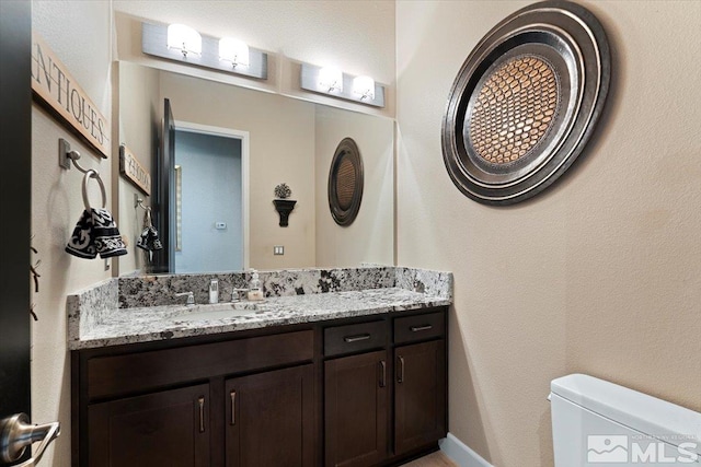 bathroom featuring toilet, vanity, and baseboards