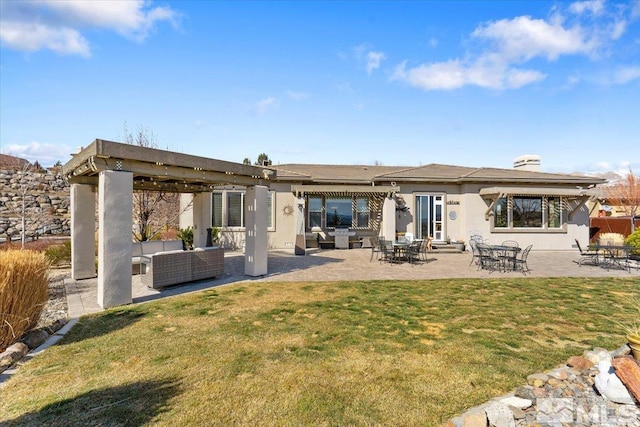 back of property with a patio, an outdoor hangout area, a lawn, and stucco siding