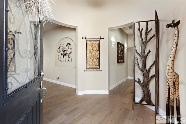 foyer with light wood-type flooring, visible vents, and baseboards