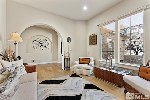 living area with recessed lighting, arched walkways, baseboards, and wood finished floors