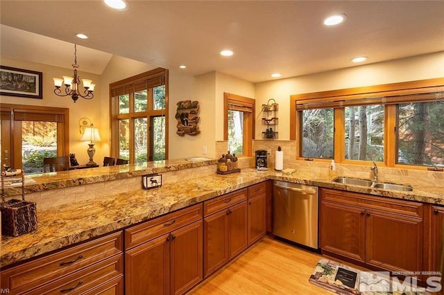 kitchen featuring brown cabinets, recessed lighting, stainless steel dishwasher, a sink, and light stone countertops