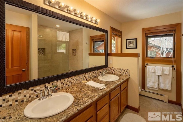 bathroom featuring double vanity, baseboard heating, a sink, and tiled shower