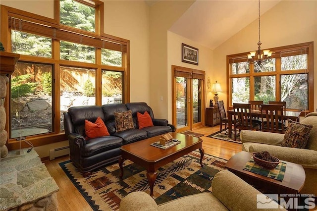 living area featuring light wood finished floors, high vaulted ceiling, baseboard heating, and a notable chandelier