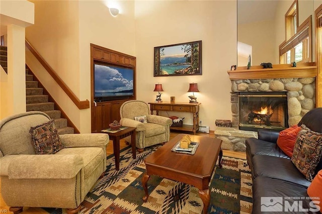 living area with wood finished floors, a fireplace, and stairs