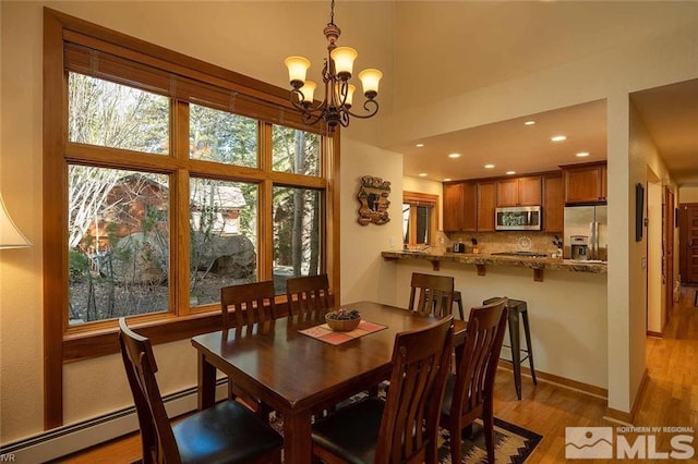 dining room featuring baseboards, light wood-type flooring, a baseboard heating unit, a notable chandelier, and recessed lighting