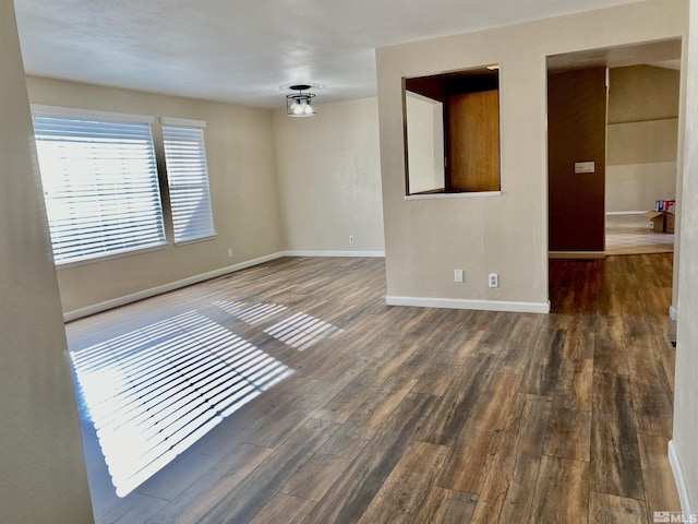 empty room featuring dark wood finished floors and baseboards