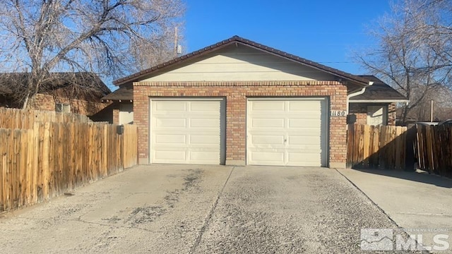 garage featuring concrete driveway and fence