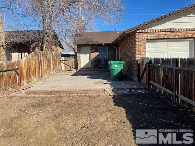 exterior space featuring an attached garage, fence, and brick siding