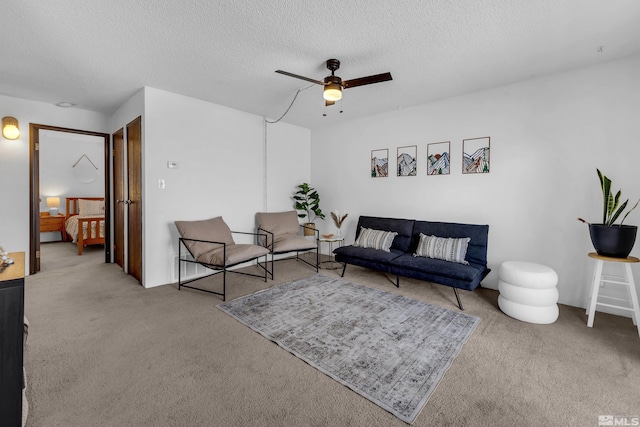 carpeted living area featuring a textured ceiling and a ceiling fan