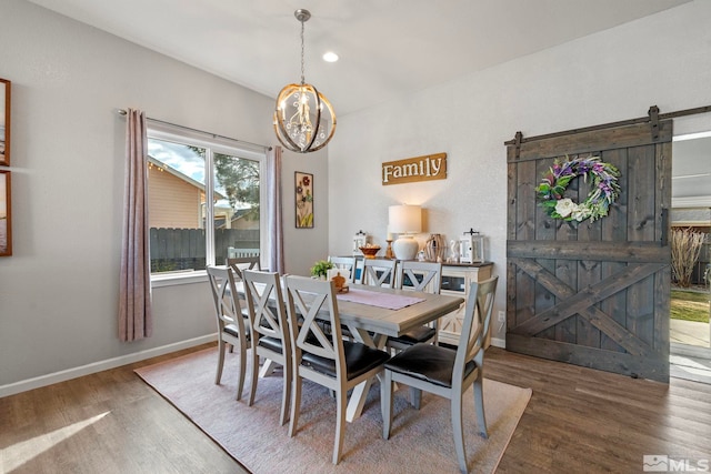 dining room featuring wood finished floors, a notable chandelier, baseboards, and a barn door