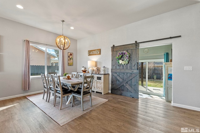 dining room with a notable chandelier, a barn door, baseboards, and wood finished floors