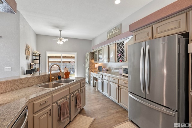 kitchen with a ceiling fan, stainless steel appliances, light countertops, light wood-style floors, and a sink