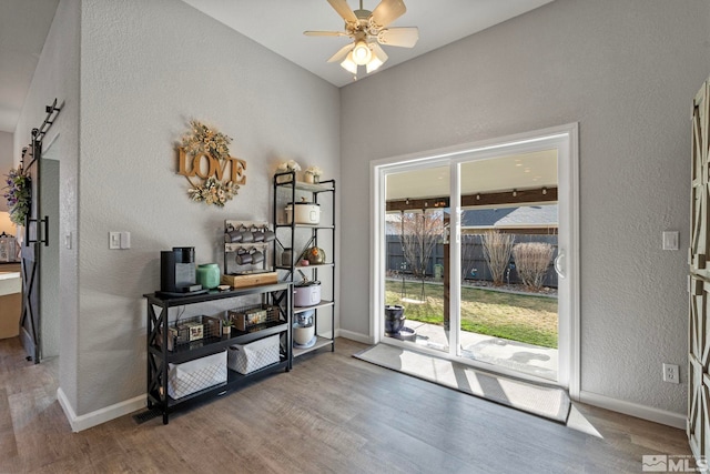 entryway with baseboards, a barn door, a ceiling fan, and wood finished floors