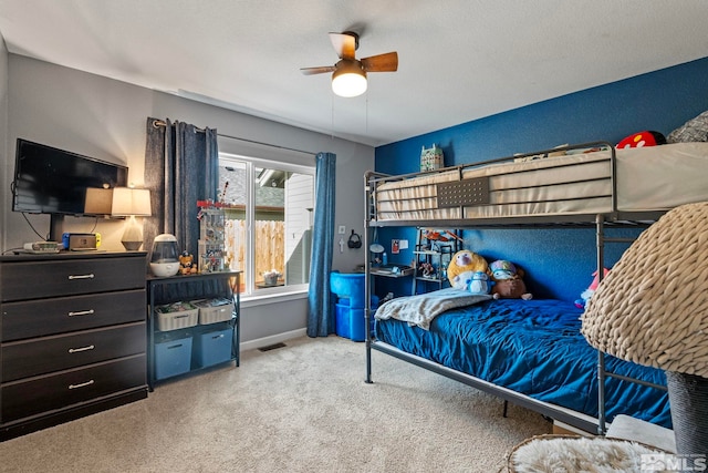 carpeted bedroom with a ceiling fan, visible vents, a textured wall, and baseboards