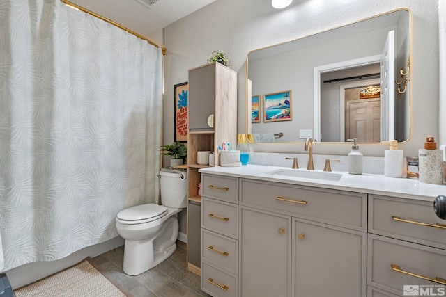 bathroom with toilet, curtained shower, wood finished floors, and vanity