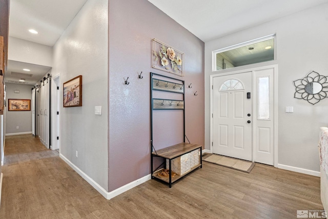 foyer entrance with recessed lighting, light wood-style flooring, baseboards, and a barn door