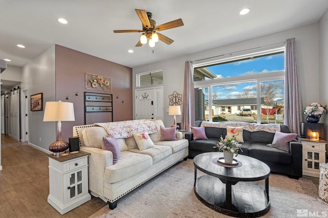 living room with baseboards, a ceiling fan, light wood-style flooring, and recessed lighting