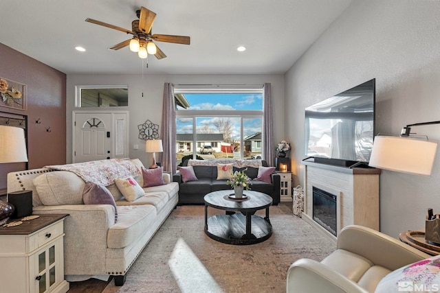 living area featuring a ceiling fan, a glass covered fireplace, and recessed lighting