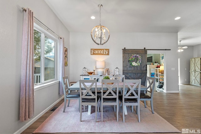 dining room with an inviting chandelier, a barn door, baseboards, and wood finished floors