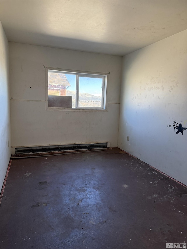 spare room featuring baseboard heating and unfinished concrete floors