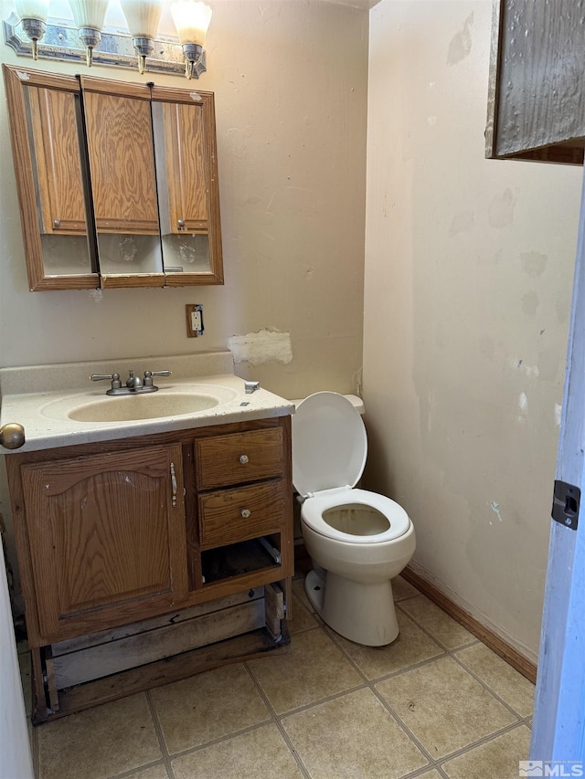 bathroom featuring tile patterned flooring, baseboards, vanity, and toilet