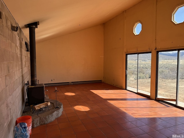 unfurnished living room with high vaulted ceiling, a wood stove, tile walls, and tile patterned floors