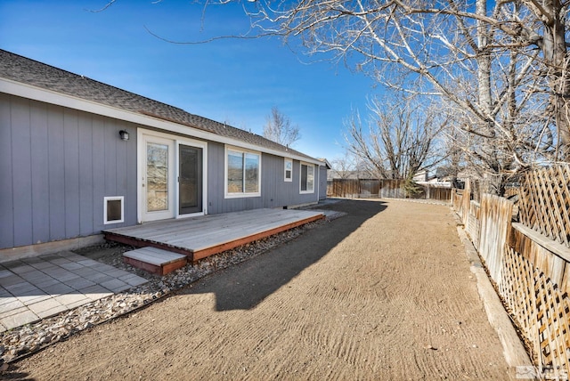 rear view of house featuring a fenced backyard, a shingled roof, and a wooden deck