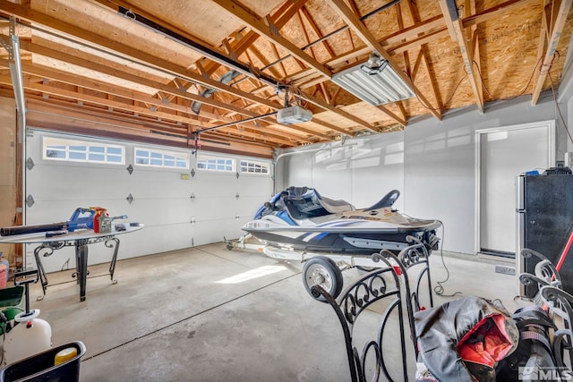 garage featuring a garage door opener and freestanding refrigerator