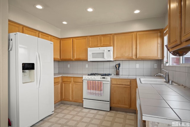 kitchen featuring a sink, white appliances, light floors, and tile counters