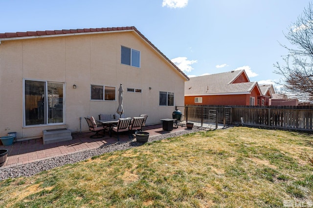 rear view of house featuring a patio area, a yard, fence private yard, and stucco siding