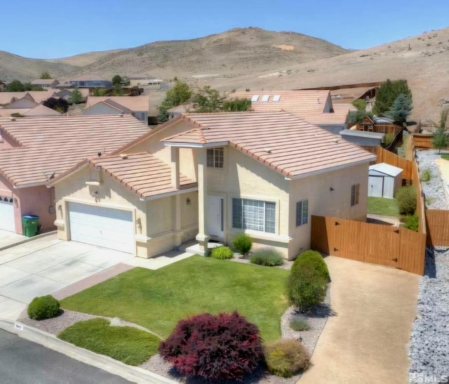 mediterranean / spanish-style house with driveway, an attached garage, stucco siding, a tiled roof, and a mountain view