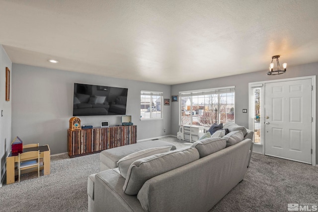 carpeted living room with a chandelier, a textured ceiling, and baseboards