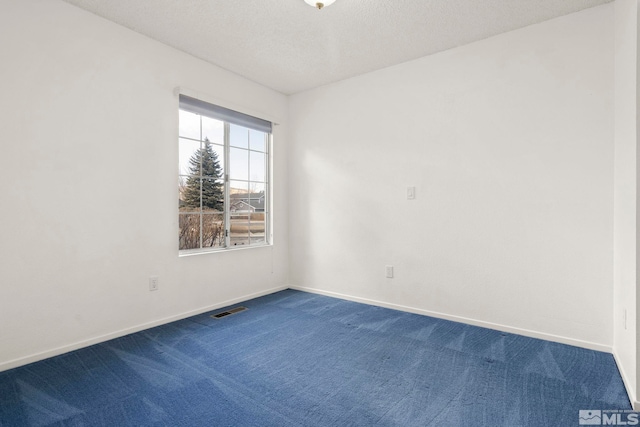 spare room with baseboards, visible vents, dark colored carpet, and a textured ceiling