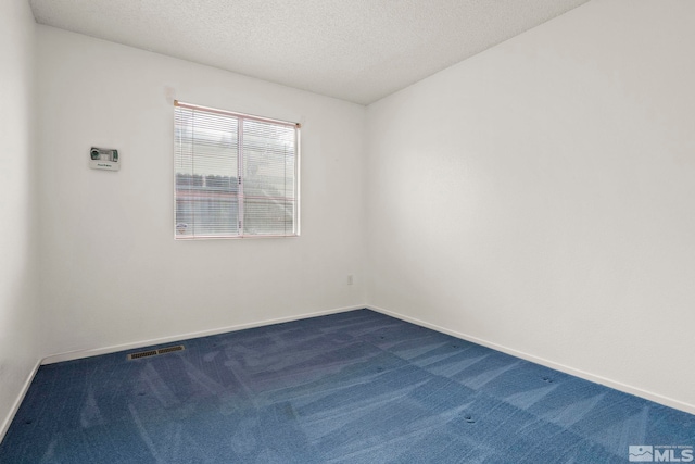 empty room with dark colored carpet, visible vents, baseboards, and a textured ceiling