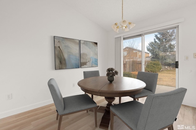 dining room with a notable chandelier, baseboards, light wood-style floors, and vaulted ceiling