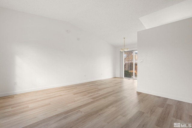 spare room with an inviting chandelier, baseboards, light wood-type flooring, and lofted ceiling