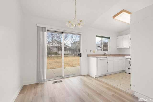 kitchen with white appliances, visible vents, light countertops, white cabinets, and light wood-style floors