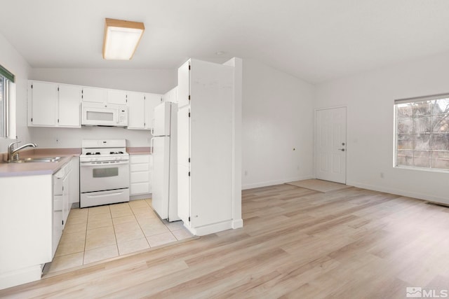 kitchen featuring a healthy amount of sunlight, white appliances, light countertops, and a sink